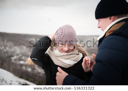 Lovers walk in the winter. A loving couple walking on a hill. He warms her hands to its warmth. He kisses her hand
