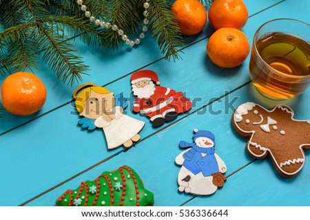 Handmade wooden Christmas tree decorations (Santa, Angel, penguin, rooster,  snowman) on a blue vintage table with Christmas tree and children's toys, tangerine, cakes. With blank and free space.