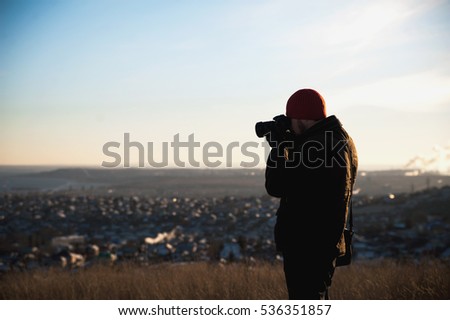 Tourist walking on the hill in winter. A tourist photographs the panorama of Saratov. A man out for a walk in the winter.