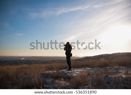 Tourist walking on the hill in winter. A tourist photographs the panorama of Saratov. A man out for a walk in the winter.