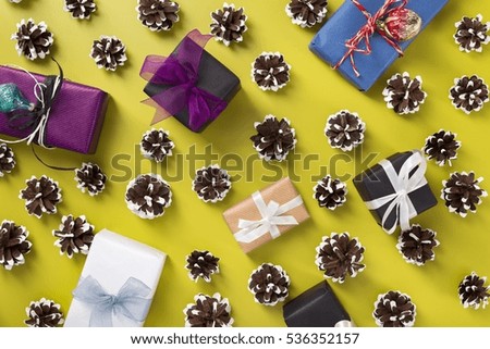 Christmas presents and painted pine cones scattered over green background, top view