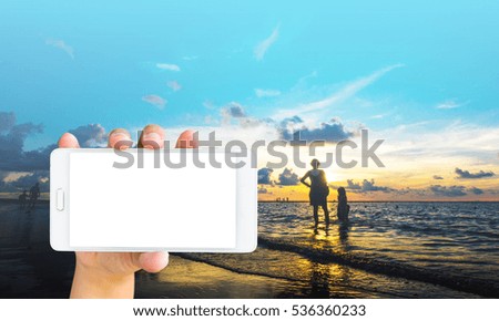 Girl use mobile phone, Happy family at sunset on the beach in Phuket, Thailand as background.