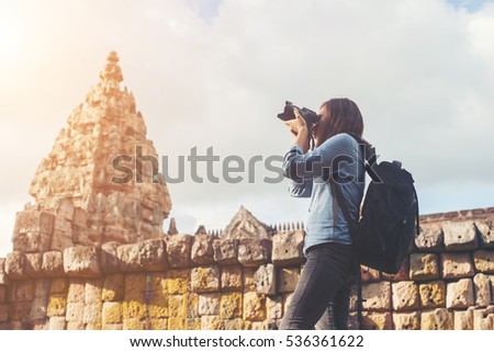 Young attractive woman photographer tourist with backpack coming to shoot photo at ancient phanom rung temple in thailand.