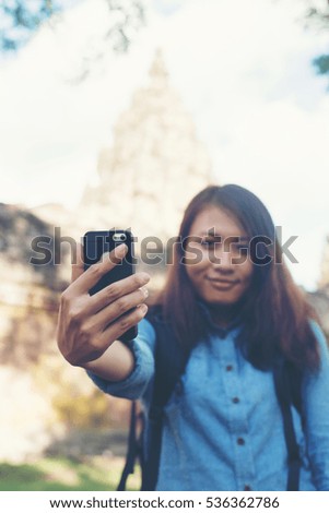 Young attractive woman taking selfie on her phone while travling at phnom rung temple in thailand.