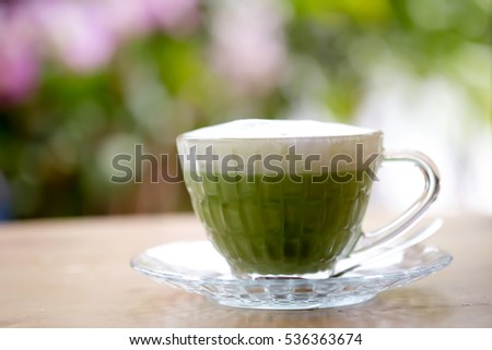 Green tea milk latte on wooden table and bokeh nature background 
