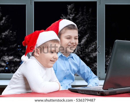 Night winter landscape outside the window. Brothers look cheerful cartoon on the laptop