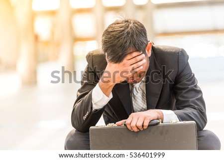 Businessman sitting on the floor near business centre at big city. He feel sad worry tired frustrated upset fail after lost work job from office . A man become unhappy and depressed person.  Royalty-Free Stock Photo #536401999