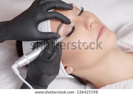 Cosmetologist making permanent makeup, close up. Tattooist making permanent make-up. Attractive lady getting facial care and tattoo. Permanent make-up tattoo at beauty salon Royalty-Free Stock Photo #536421598