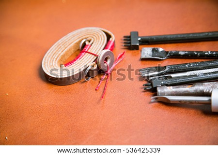 Art work of genuine leather camera strap handmade with meatal tool on leather  background