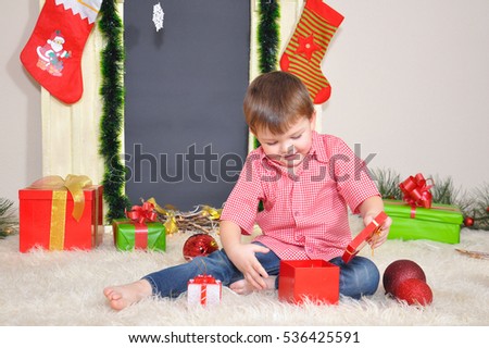 Little Kid opening Christmas gift in front of fireplace
