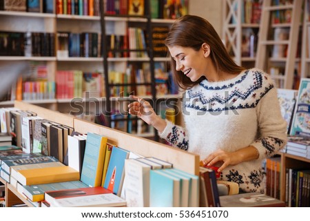 Portrait of a beautiful brunette woman looking for a book in store Royalty-Free Stock Photo #536451070
