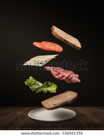 Delicious Sandwich with floating ingredients on the wood table black background Royalty-Free Stock Photo #536461396