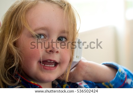 Baby caucasian girl toddler joyful and playing on the cell phone with innocence and happiness at home