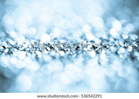 blurred blue bokeh of Christmas lights. Magic holiday abstract glitter background with blinking stars and falling snowflakes.