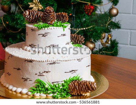 big white cake on the table against the background of the Christmas tree