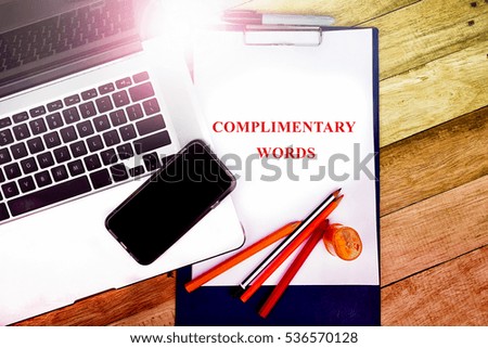 COMPLIMENTARY WORDS word, text at notepad in wooden table background , retro concepts in wooden with notebook and smartphone  