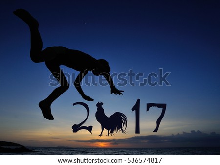 Silhouettes on the beach with a background of sunset sky: little boy jumps from dad's hands and flutters over the water. There are numbers 2017 written in the air - year of the rooster is coming up