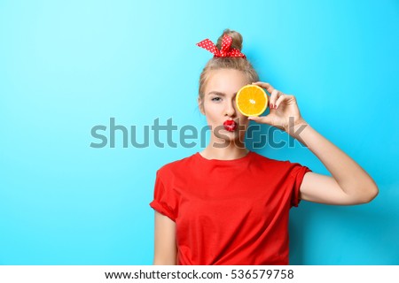 Young beautiful woman with orange on blue background