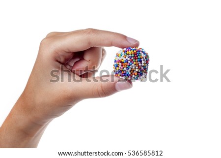 Child's hand holding a traditional candy from Brazil, a colored brigadier called in Portuguese brigadeiro.