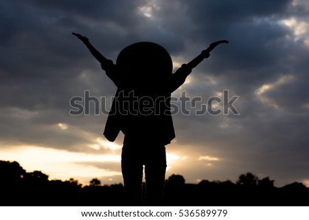 Silhouette Happy woman with her arms outstretched enjoying sunset.