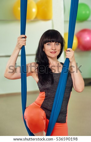 middle-aged woman with aerial yoga hammock