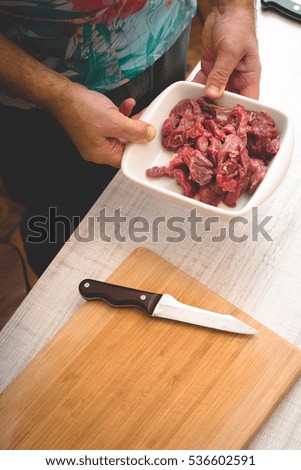 Man hold the plate with raw sliced meat