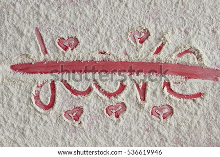 Word love written and crossed out on the flour background 