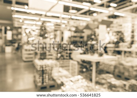 Blurred row, shelves of plastic Christmas bell ornaments, garlands, lightings and artificial Christmas tree decoration for sale in large furniture warehouse. Bokeh lights background. Vintage tone