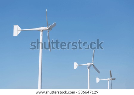 Three white wind turbine for energy generator and reserve on blue sky during sunny day
