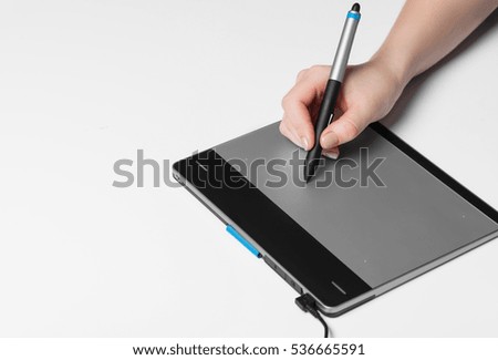 Girl draws on the black graphic tablet
