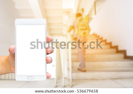 Man use mobile phone, blur image of the man backpack walking up stairs as background.