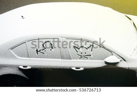View from above of a car covered with snow and cartoon faces of a mice and a cat - children draw 
