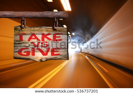Take vs give motivational phrase sign on old wood with blurred background