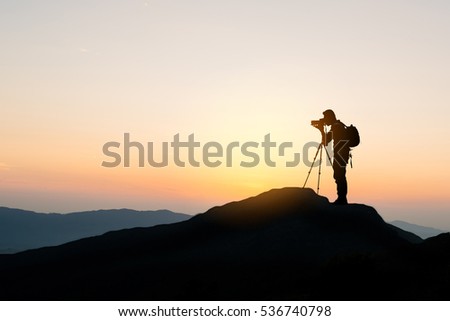 silhouette of photographer on top of mountain at sunset background