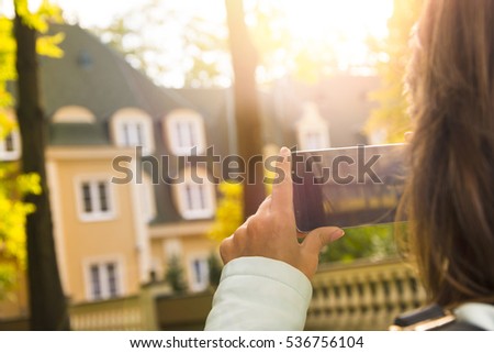 Woman taking a photo with her smartphone at the park.
