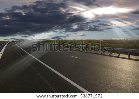 Asphalt road High way Empty curved road clouds and sky at sunset