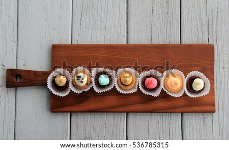 Seven bite-sized treats for dessert, offered in little muffin tins and set on wood background. Royalty-Free Stock Photo #536785315