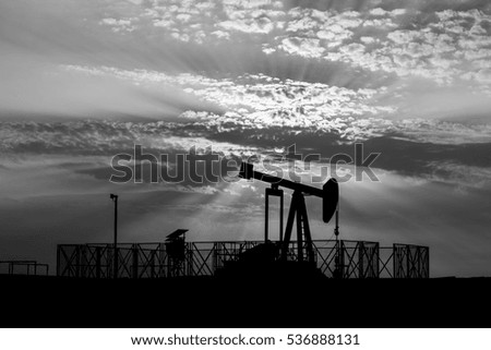 Silhouette of crude oil BPU pump in oilfield at sunset - black and white 
