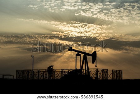 Silhouette of crude oil BPU pump in oilfield at sunset 