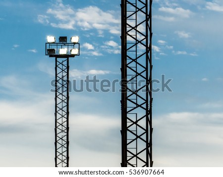 Floodlight on light tower for illumination of a stadium pictured at twilight and blue skies.