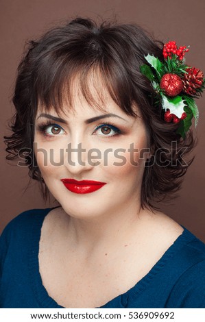 Beautiful dark haired woman with stunning colorful festive make up and red lips, dark background, closeup fashion photo, Christmas decoration in hair