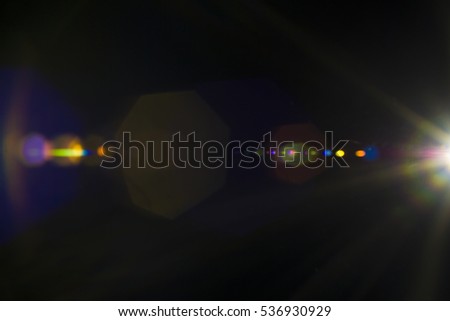 Solar camera lens flare light create ring of objective iris shapes of different rainbow colors depending on used antireflection coating of each lens surface on dark black background. Creative lighting