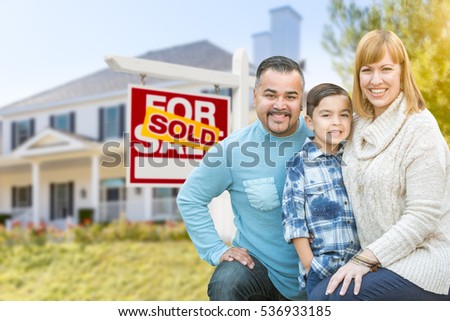 Happy Mixed Race Hispanic and Caucasian Family Portrait In Front of House and Sold For Sale Real Estate Sign.