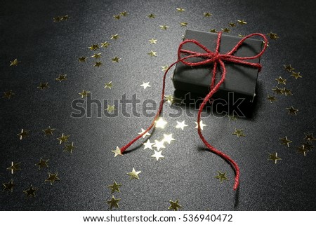 Christmas present with shiny golden stars on a black background