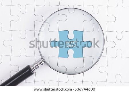 Business Concept - Magnifier Glass on white puzze with HAPPY 2017 Word