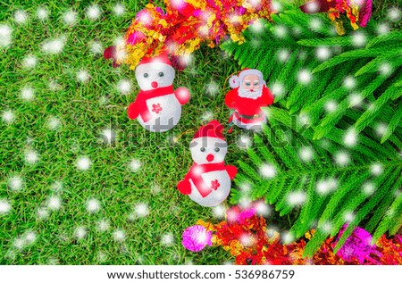 Snow man on green lawn with Christmas tree