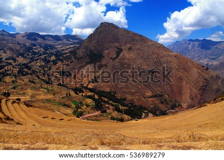 top view of the big circled terraces of the inca ruins of pisac in the sacred valley in peru , with a mountain panorama and blue sky