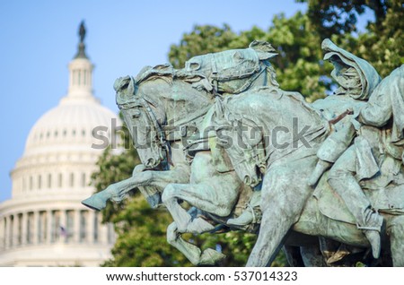 Bronze memorial of horses (Artillery, 1912) charging forward with the US Capitol Building dome under blue sky in the background in Washington, DC Royalty-Free Stock Photo #537014323