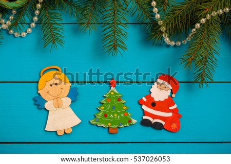 Handmade wooden Christmas tree decorations (Santa, Angel, Christmas tree, snowman, penguin ) on a blue vintage table with Christmas tree. With blank and free space.
