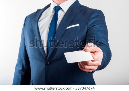 Businessman in suit is showing business card on white background